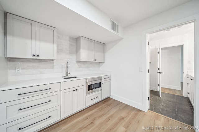 kitchen with visible vents, backsplash, light countertops, and a sink