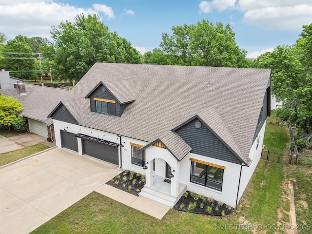modern inspired farmhouse featuring concrete driveway, a shingled roof, an attached garage, fence, and a front lawn