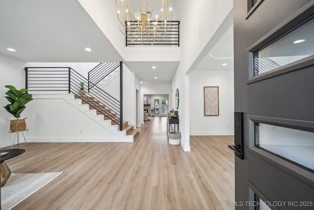 foyer with light wood-style floors, baseboards, recessed lighting, a high ceiling, and stairs