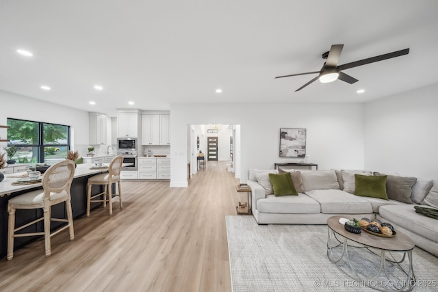 living area with a ceiling fan, light wood-style flooring, and recessed lighting