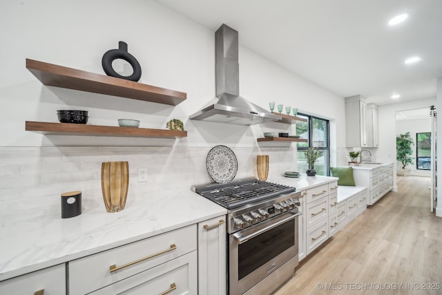 kitchen with tasteful backsplash, high end stainless steel range oven, open shelves, and wall chimney range hood