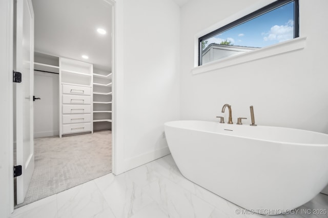full bathroom with a walk in closet, baseboards, a freestanding bath, and recessed lighting