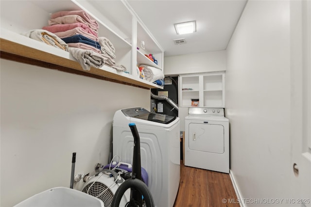 laundry room with separate washer and dryer, laundry area, visible vents, baseboards, and wood finished floors