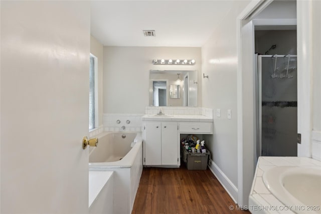 bathroom featuring vanity, a bath, a stall shower, visible vents, and wood finished floors