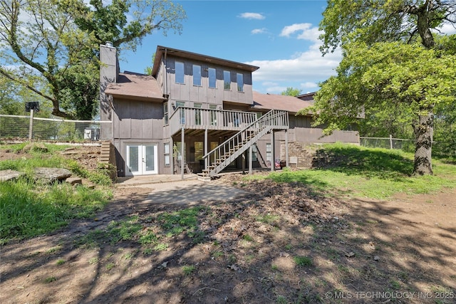 back of property with a deck, a chimney, fence, stairway, and french doors