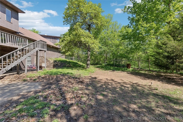 view of yard with a wooden deck, stairway, and fence