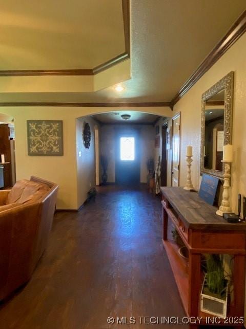 interior space featuring wood finished floors, crown molding, baseboards, and arched walkways