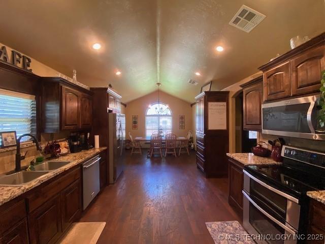 kitchen with lofted ceiling, a sink, appliances with stainless steel finishes, visible vents, and dark wood finished floors