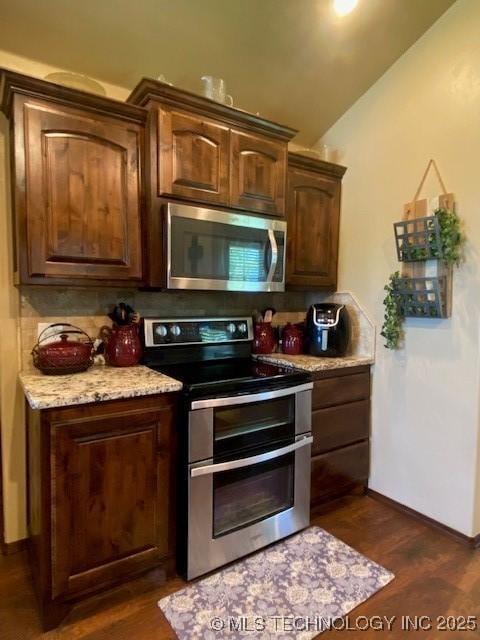 kitchen with lofted ceiling, stainless steel appliances, baseboards, dark wood finished floors, and backsplash