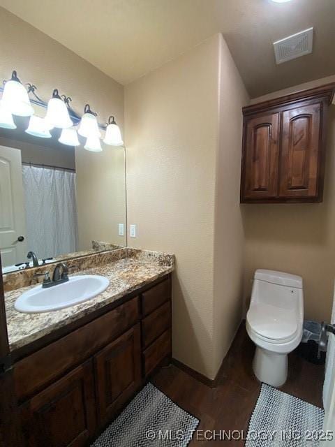 full bath featuring toilet, vanity, visible vents, and wood finished floors
