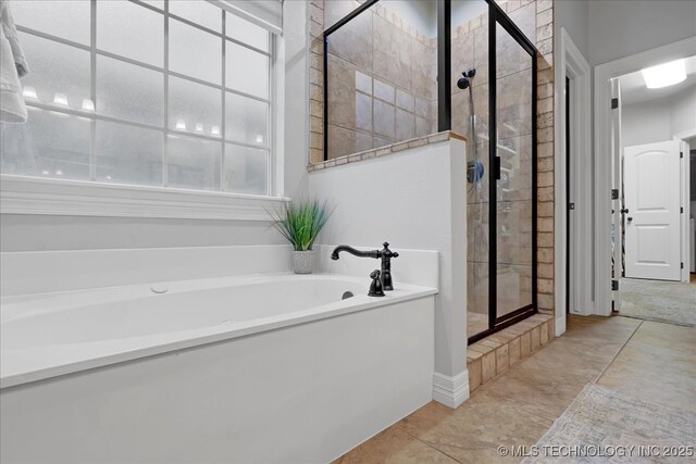 bathroom with a shower stall, tile patterned flooring, and a bath