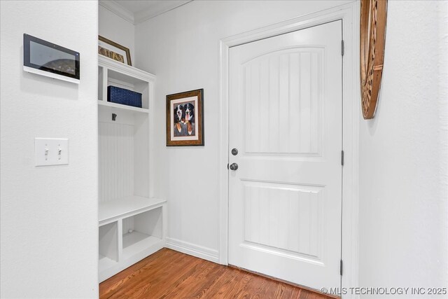 mudroom with ornamental molding, wood finished floors, and baseboards