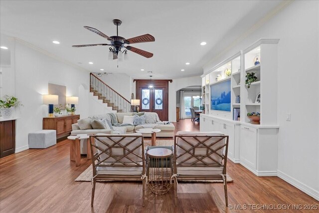 living room featuring recessed lighting, ceiling fan, light wood-type flooring, baseboards, and arched walkways