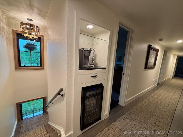 210 Woods Ln, Ardmore, OK 73401 - hallway featuring wood finished floors, an upstairs landing, a notable chandelier, visible vents, and baseboards