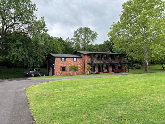 view of front of property with brick siding, a front lawn, and driveway