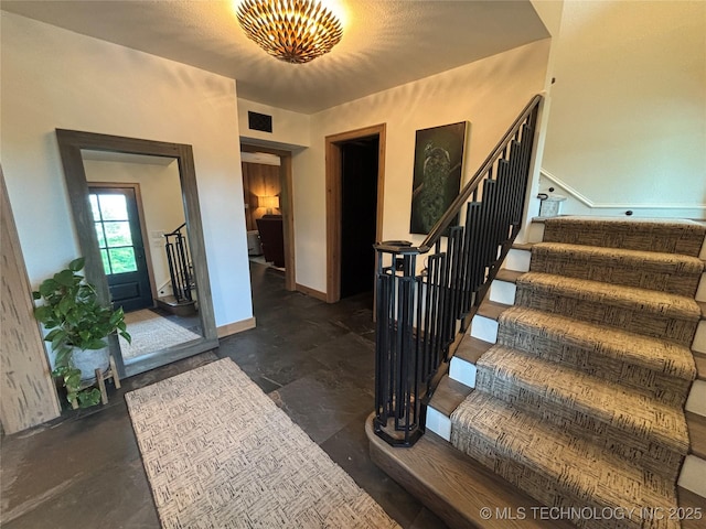 foyer with baseboards, visible vents, and stairs