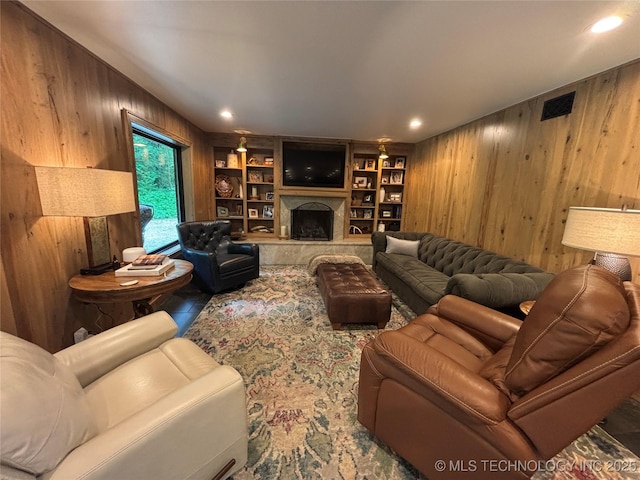 living room featuring visible vents, wooden walls, a fireplace, and built in features