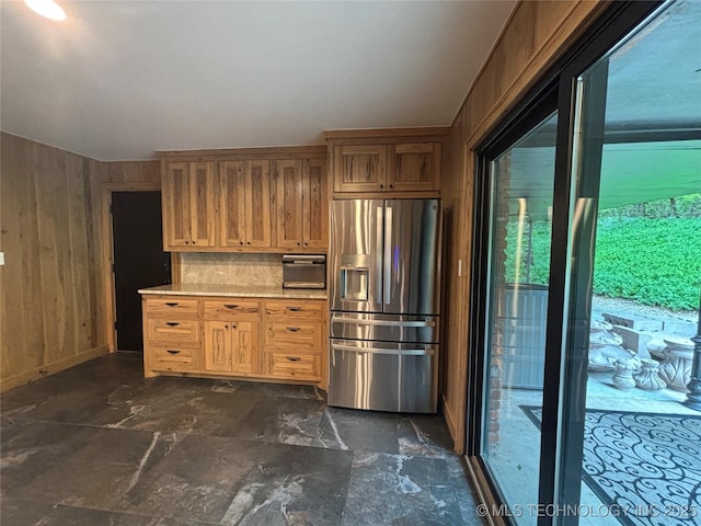 kitchen with wooden walls, stainless steel refrigerator with ice dispenser, and light countertops