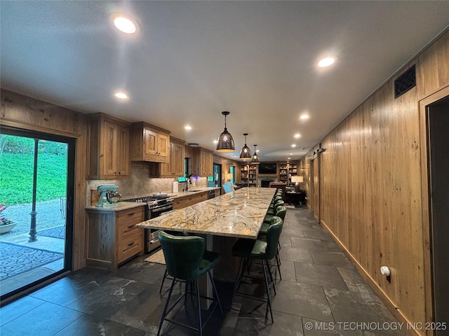 kitchen with wood walls, a spacious island, gas range, a kitchen bar, and recessed lighting