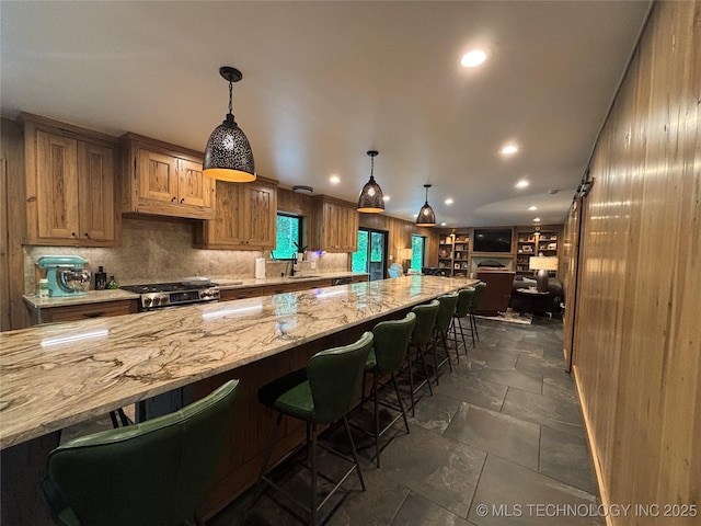 kitchen with a kitchen breakfast bar, stainless steel gas range oven, light stone countertops, recessed lighting, and backsplash