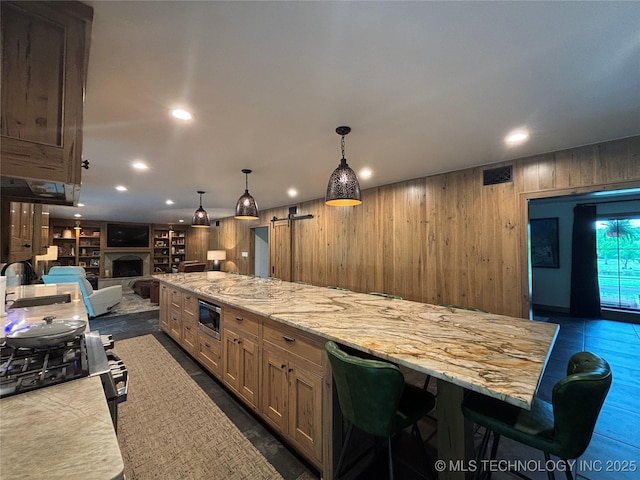 kitchen with stainless steel microwave, wood walls, visible vents, open floor plan, and a fireplace
