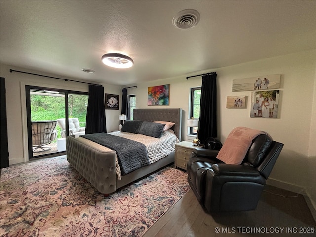 bedroom with wood finished floors, visible vents, access to outside, and multiple windows