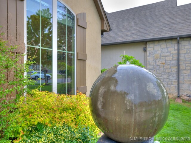 16321 E 48th Pl, Tulsa, OK 74134 - details with stone siding, roof with shingles, gutters, stucco siding, and a downspout