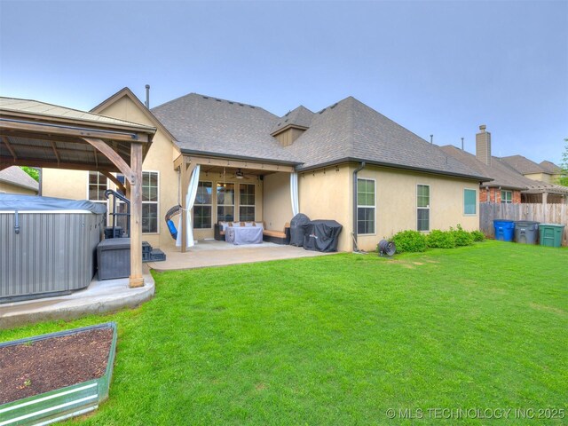 16321 E 48th Pl, Tulsa, OK 74134 - rear view of house featuring stucco siding, ceiling fan, a hot tub, a patio, and a lawn