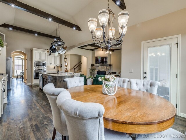 16321 E 48th Pl, Tulsa, OK 74134 - dining area with a chandelier, lofted ceiling with beams, arched walkways, dark wood finished floors, and a fireplace