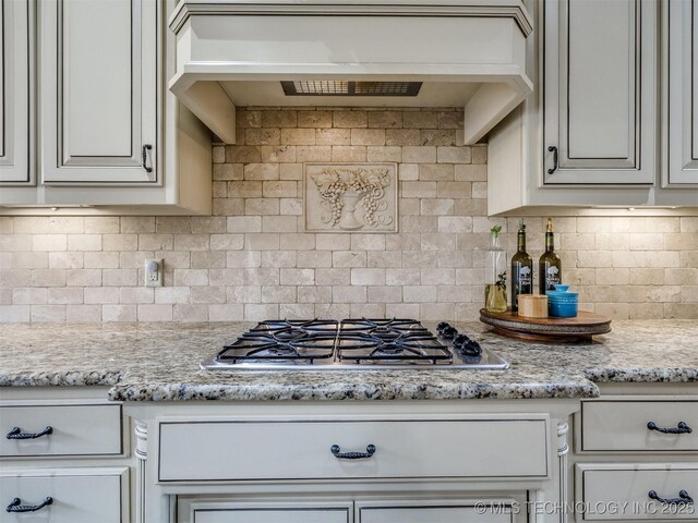 16321 E 48th Pl, Tulsa, OK 74134 - kitchen featuring light stone countertops, stainless steel gas stovetop, under cabinet range hood, and tasteful backsplash