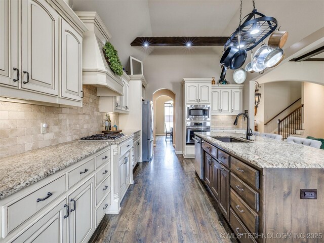 16321 E 48th Pl, Tulsa, OK 74134 - kitchen featuring decorative backsplash, a sink, appliances with stainless steel finishes, dark wood-style floors, and arched walkways