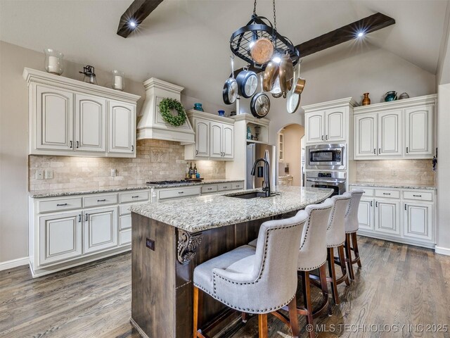 16321 E 48th Pl, Tulsa, OK 74134 - kitchen featuring tasteful backsplash, arched walkways, stainless steel appliances, a sink, and dark wood-style floors