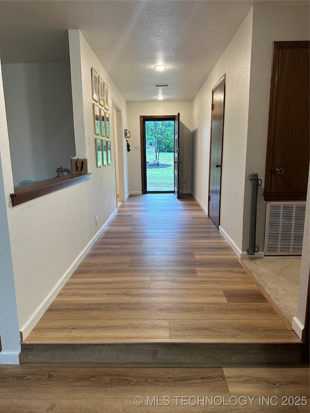 2621 Chuckwa St, Durant, OK 74701 - hall with a textured wall, wood finished floors, baseboards, and a textured ceiling