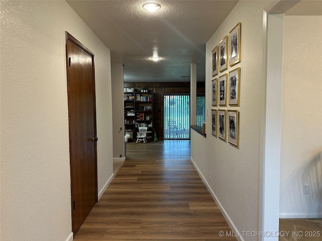 2621 Chuckwa St, Durant, OK 74701 - hallway with dark wood-style flooring, baseboards, a textured ceiling, and a textured wall