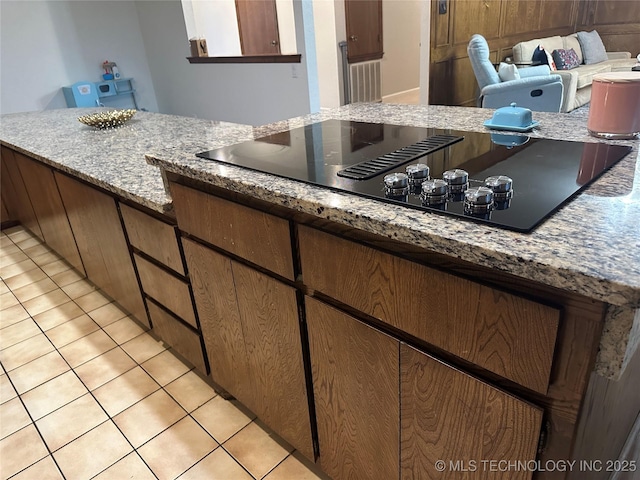 2621 Chuckwa St, Durant, OK 74701 - kitchen with black electric stovetop, light stone counters, and light tile patterned flooring