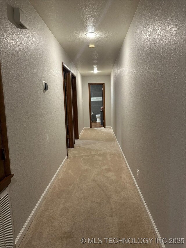 2621 Chuckwa St, Durant, OK 74701 - hall featuring a textured wall, carpet floors, baseboards, and a textured ceiling