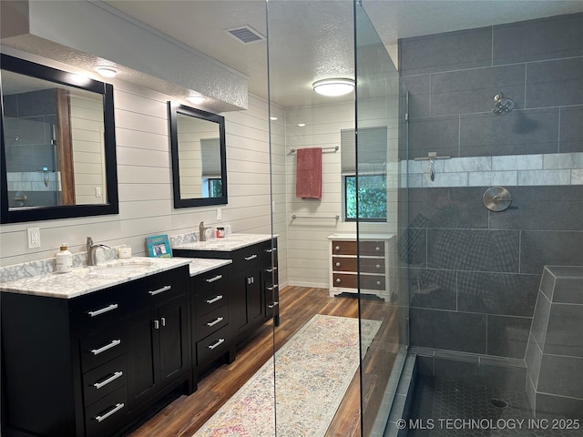2621 Chuckwa St, Durant, OK 74701 - bathroom featuring a walk in shower, wood finished floors, two vanities, and a textured ceiling