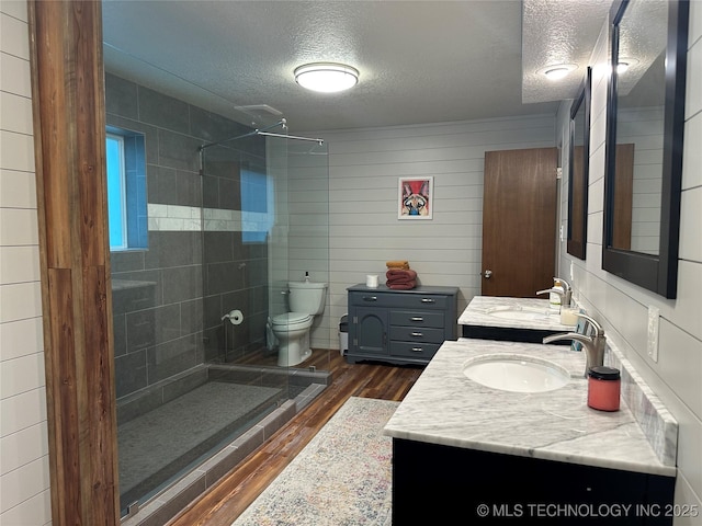 2621 Chuckwa St, Durant, OK 74701 - full bathroom featuring a textured ceiling, wood finished floors, tiled shower, toilet, and vanity