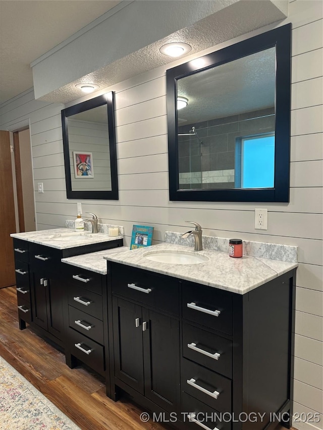 2621 Chuckwa St, Durant, OK 74701 - full bathroom featuring wood finished floors, wood walls, two vanities, tiled shower, and a textured ceiling