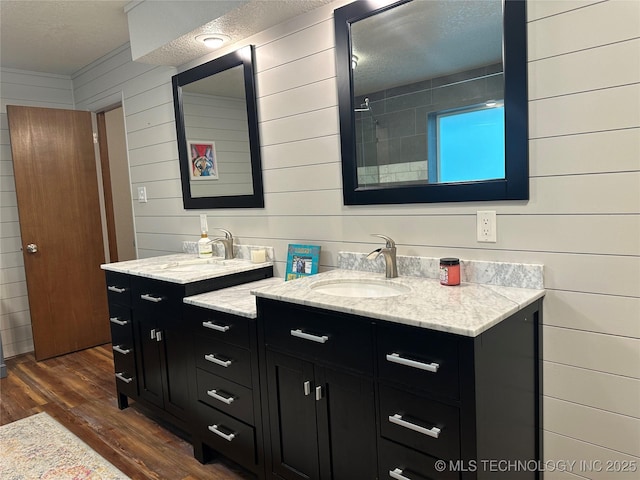 2621 Chuckwa St, Durant, OK 74701 - bathroom with a textured ceiling, wood finished floors, wood walls, two vanities, and a tile shower