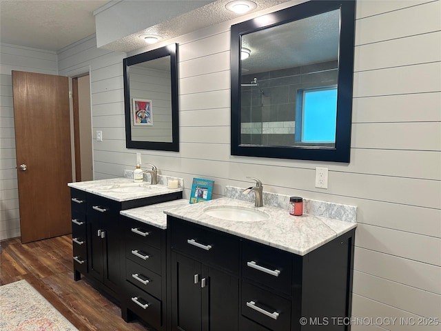 2621 Chuckwa St, Durant, OK 74701 - bathroom with wood finished floors, a textured ceiling, wood walls, and two vanities