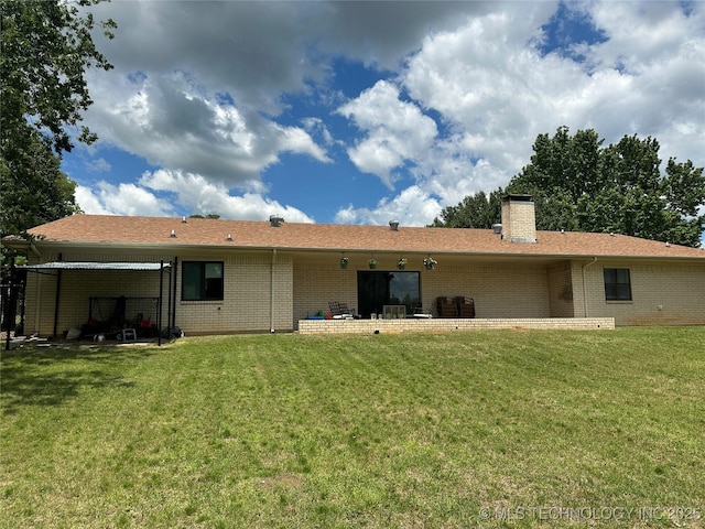 2621 Chuckwa St, Durant, OK 74701 - rear view of house featuring brick siding, a yard, and a chimney