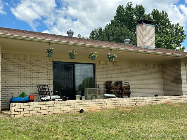 2621 Chuckwa St, Durant, OK 74701 - rear view of house with brick siding, a chimney, and a lawn