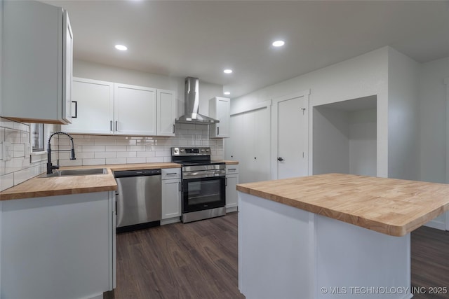 kitchen with dark wood-style flooring, wooden counters, wall chimney exhaust hood, a sink, and appliances with stainless steel finishes