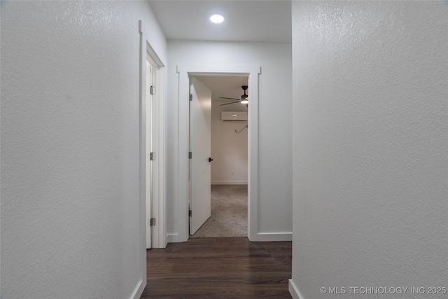 corridor with a textured wall, wood finished floors, baseboards, recessed lighting, and a wall mounted AC
