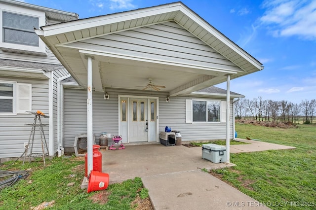 entrance to property with a patio, ceiling fan, and a yard