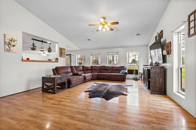living area with a ceiling fan, visible vents, wood finished floors, and a fireplace