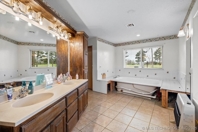 bathroom with a garden tub, double vanity, a sink, and tile patterned floors