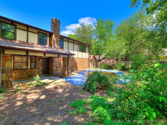 exterior space with a patio, stone siding, a chimney, stucco siding, and fence