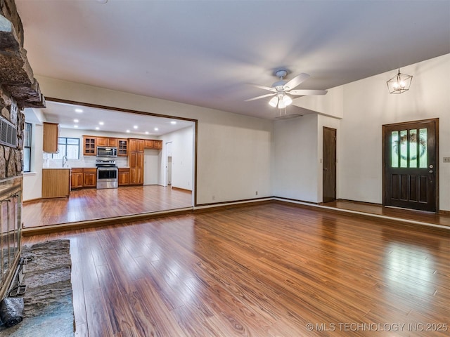unfurnished living room with recessed lighting, a ceiling fan, dark wood-style flooring, and a sink